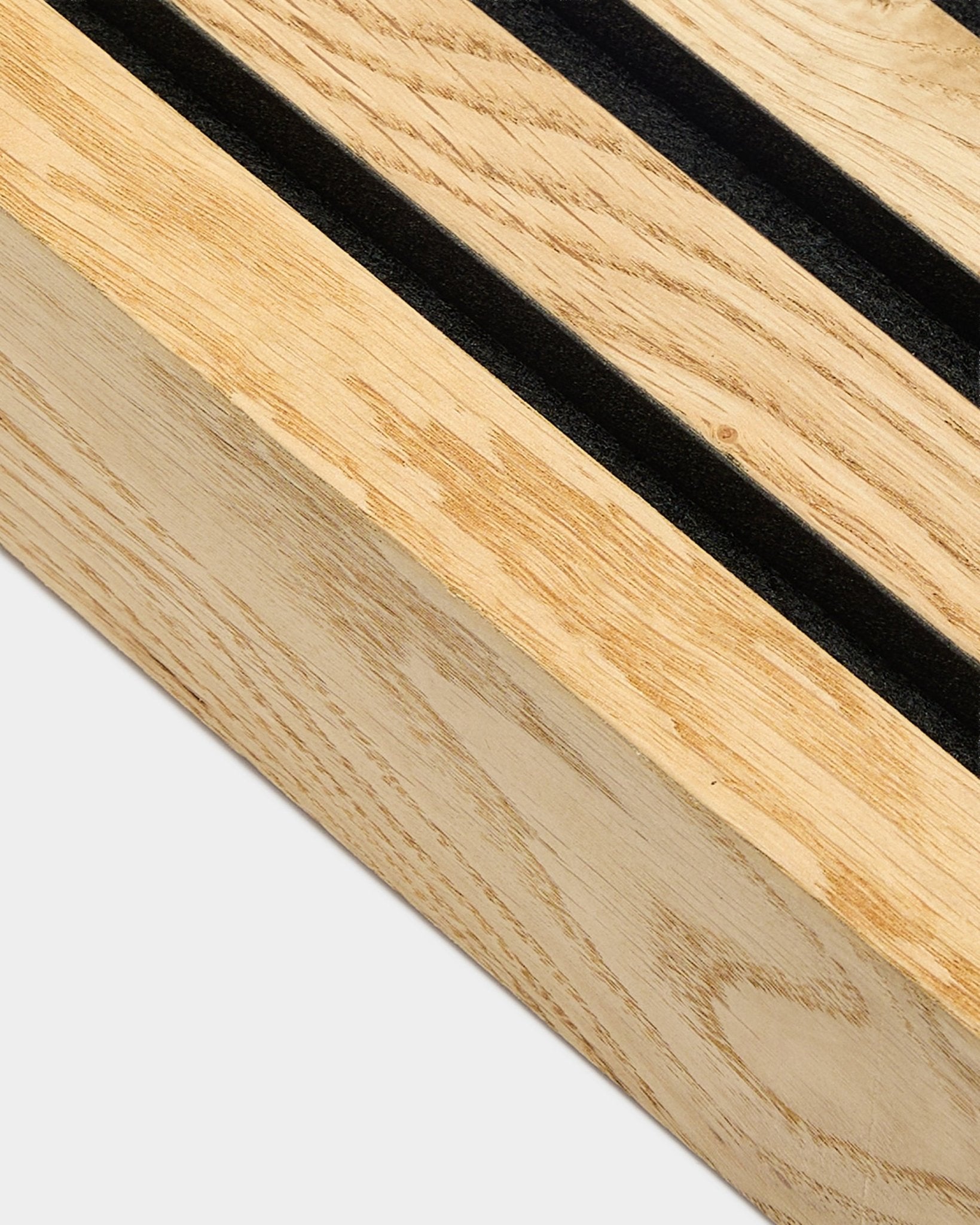 Close-up of a WoodUpp Akupanel end lamella in Rustic Natural Oak, 6.7 cm, featuring parallel black slots and an MDF frame for acoustic wall installation.